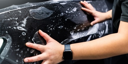 Persona che applica pellicola paint protection film all'auto
