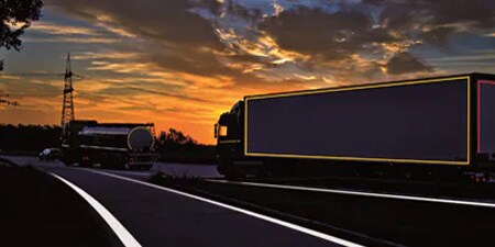 Camion su una strada buia con marcature di visibilità in evidenza
