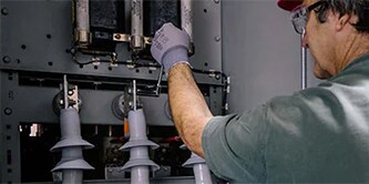 Uomo che monitora componenti elettrici per garantire un funzionamento affidabile rete elettrica.
