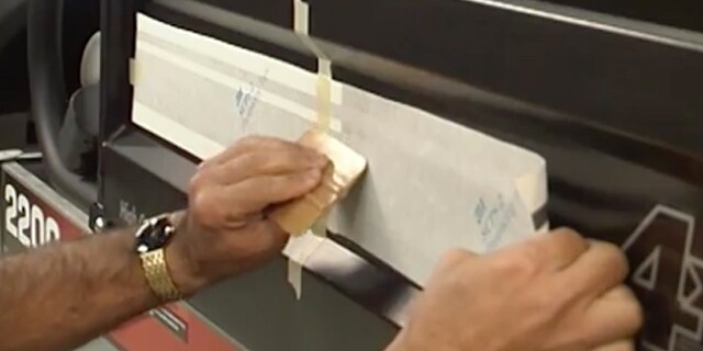 Applicazione di una pellicola per wrapping 3M alla parte posteriore di una macchina nera con un applicatore piano