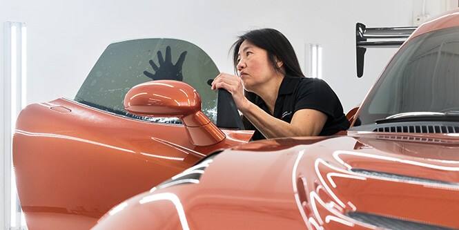 Donna che installa oscuramento vetri su finestrino lato passeggero su auto sportiva

