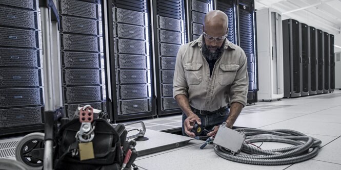 operaio in un data center che installa canaline elettriche sotto il pavimento

