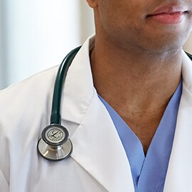 Stetoscopio Littmann indossato correttamente sopra il bavero di un camice bianco da laboratorio, per impedire al tubo di entrare in contatto con il collo del medico.