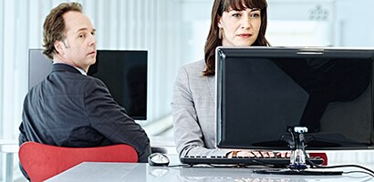 Osservatore indiscreto che guarda un monitor oltre la propria spalla
