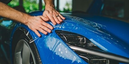 Persona che applica pellicola paint protection film all'auto
