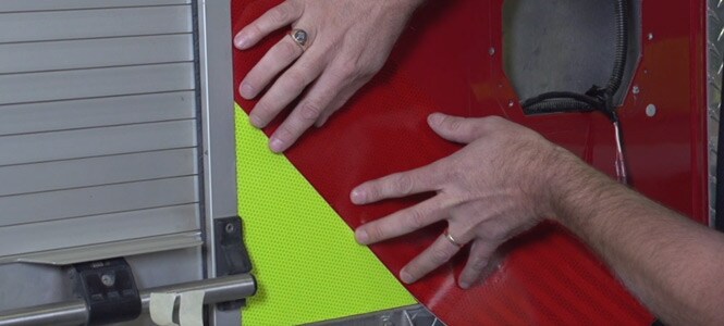  Persona che applica delle pellicole riflettenti a un camion dei pompieri
