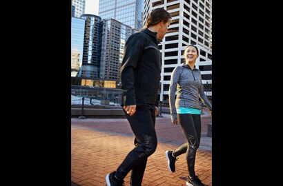 Un uomo e una donna che camminano, conversano e si allenano in città mentre indossano materiale riflettente elastico 3M Scotchlite C790 Carbon Black