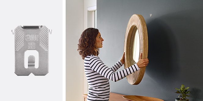 Donna che appende uno specchio e usa 3M CLAW™ Gancio appendiquadri per cartongesso
