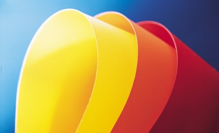 Campioni curvi di pellicole a colori solidi gialle, arancioni e rosse su sfondo blu
