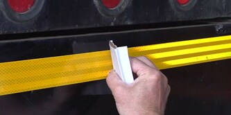 Persona che applica il nastro di visibilità al camion
