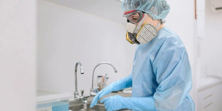 Persona che usa prodotti chimici sanitari e un respiratore riutilizzabile per disinfezione
