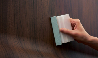 Una persona che applica una pellicola architettonica con venature del legno
