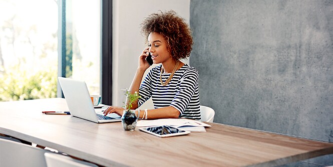 Persona al telefono mentre utilizza un laptop
