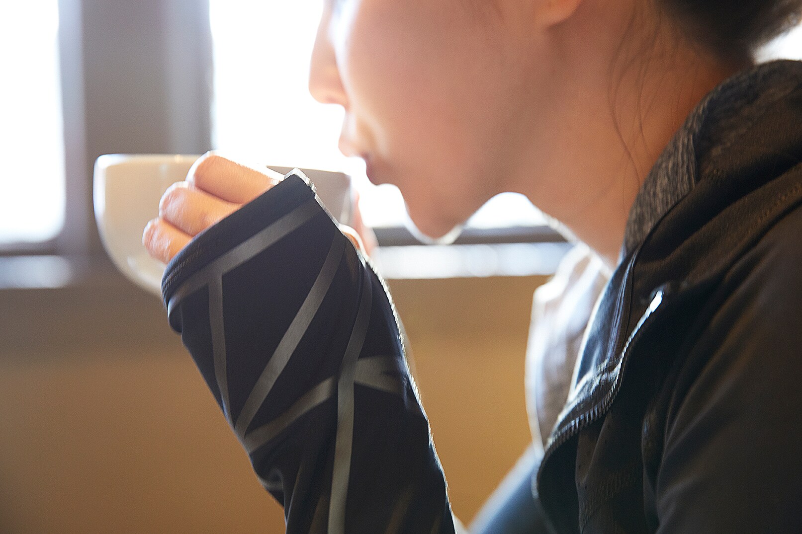 Donna che sorseggia un caffè, primo piano del materiale riflettente elastico nero Scotchlite sulla manica della donna con la tazzina di caffè
