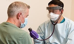 Medico che indossa un DPI che parla con un paziente
