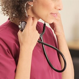 Infermiera che inserisce nelle orecchie le olivette di uno stetoscopio 3M Littmann Classic III.