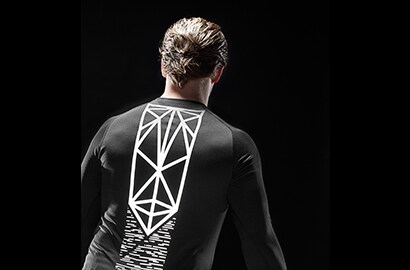 Uomo in piedi al buio che indossa una maglia nera illuminata, realizzata con materiale riflettente elastico nero 3M Scotchlite
