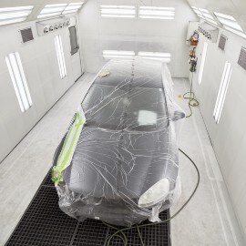 Un'auto in una cabina di verniciatura durante il processo di essiccazione forzata