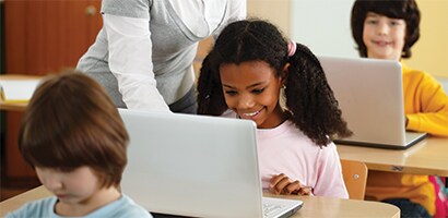 Bambini in classe che usano computer portatili
