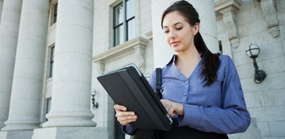 Donna che usa un tablet davanti a un edificio della pubblica amministrazione
