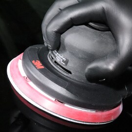 Immagine di una mano con guanto nero e levigatrice rotorbitale elettrica e pneumatica 3M™ 