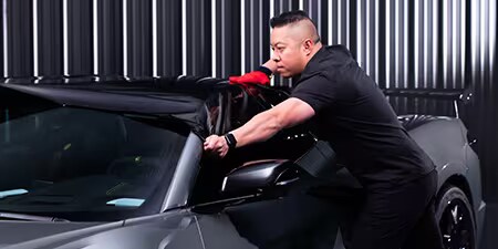 Installatore car wrap che applica la pellicola sul tetto di un veicolo.
