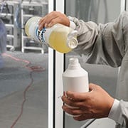 Uomo che mescola sapone liquido con acqua utilizzando un flacone spray