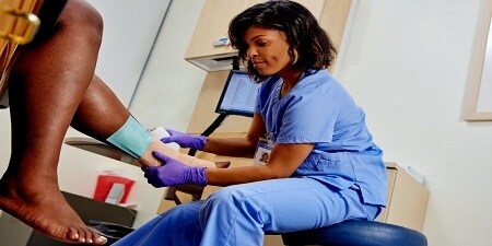 operatore sanitario che controlla un'ulcera venosa alla gamba
