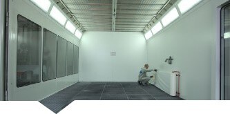  Uomo che applica rotolo protettivo Dirt Trap 3M sulle pareti di una cabina di verniciatura
