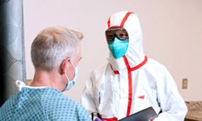 Medico che indossa un DPI che parla con un paziente
