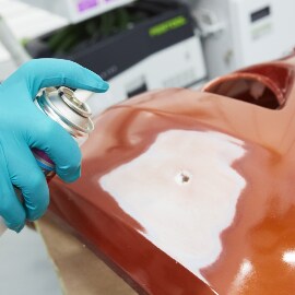 Spruzzatura del promotore di adesione su un'area lesionata di un paraurti