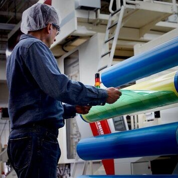 lavoratore che rimuove una piastra flessografica da una piastra flessografica su cilindro