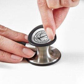 Dita che rimuovono la membrana fluttuante dalla campana di uno stetoscopio 3M Littmann Classic III.