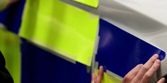 Persona che applica pellicole riflettenti su un'auto della polizia
