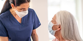Medico che indossa un DPI e che parla con un paziente che indossa un DPI

