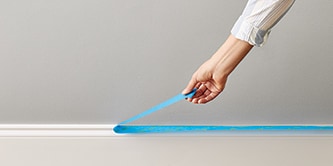 Persona che rimuove il nastro adesivo ScotchBlue™ da un battiscopa
