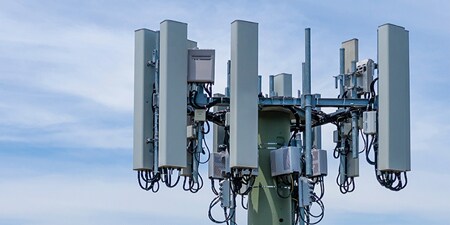 Parte superiore di una torre dell'antenna contro un cielo blu.

