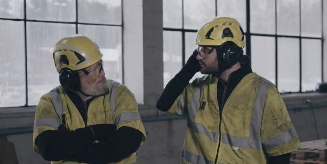 Lavoratore con elmetto e cuffie auricolari che guarda lontano
