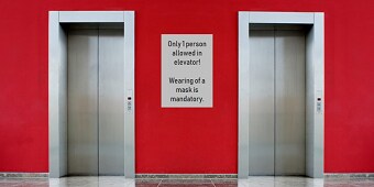Una parete rossa e un cartello bianco tra la porta dell'ascensore
