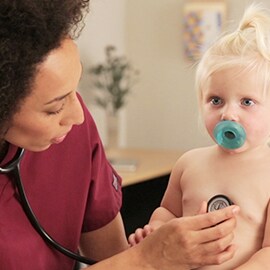 Infermiera pediatrica che ausculta il torace di un neonato con uno stetoscopio 3M Littmann Classic III.
