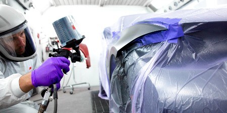 verniciatore che spruzza un'auto con un sistema di pistola spray 3M
