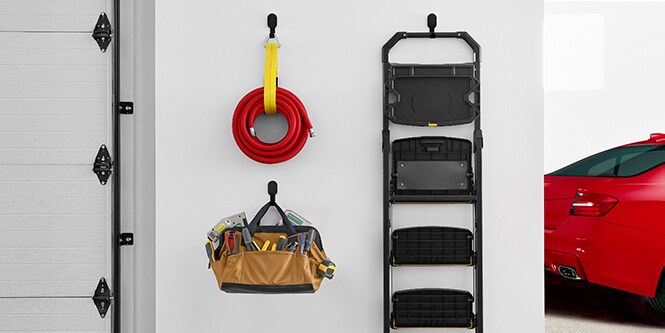 Tubo flessibile, scala e sedia appesi alla parete del garage con ganci per cartongesso 3M CLAW™.
