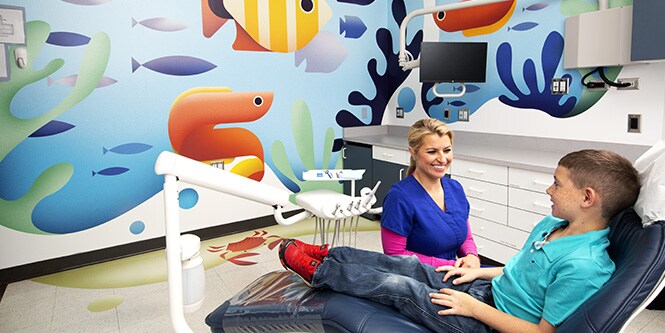 Bambino e dentista nello studio con illustrazione dell'oceano stampata su pellicole 3M.
