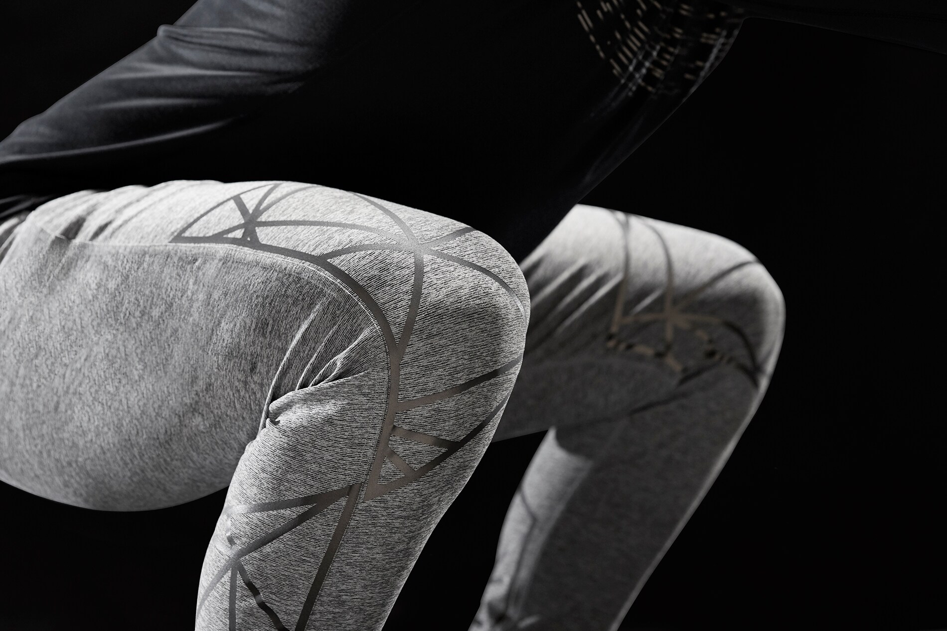 Uomo che esegue una serie di squat indossando materiale riflettente elastico 3M Scotchlite che si allunga sulle ginocchia, non illuminato