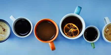 Foto dall'alto di tazze di caffè colorate con diverse bevande calde.
