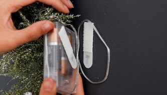 Persona che appende la batteria della decorazione di Natale a parete
