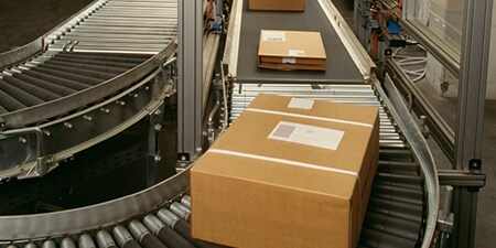 Tre pacchi pronti per la spedizione su un nastro trasportatore.
