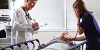 Un medico al letto del paziente, un infermiere utilizza lo stetoscopio sul paziente
