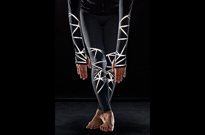 Donna atletica protesa in avanti che indossa abbigliamento tecnico con materiale riflettente elastico 3M Scotchlite C790 Carbon Black illuminato