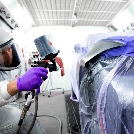 Verniciatore che spruzza un'area dell'auto utilizzando l'aerografo ad alte prestazioni di 3M